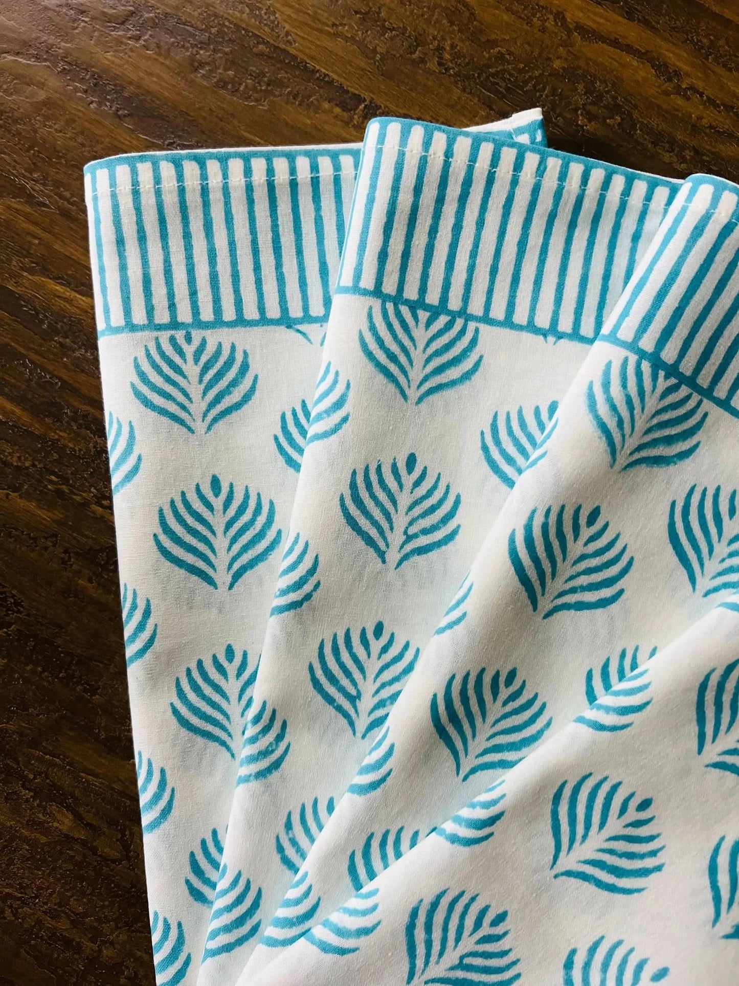 Set of four turquoise Coral Flame napkins by Christina Dickson Home featuring vibrant coral flame pattern.