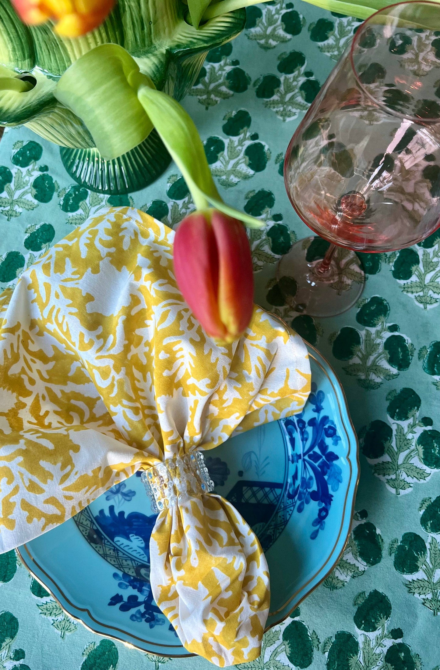 Emerald green Poms tablecloth by Christina Dickson Home, 120x70 inches rectangle, showing vibrant fabric with white pom detail.