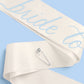 Bride To Be sash from xo, Fetti with white satin fabric and gold lettering, designed for bridal celebrations and bachelorette parties.