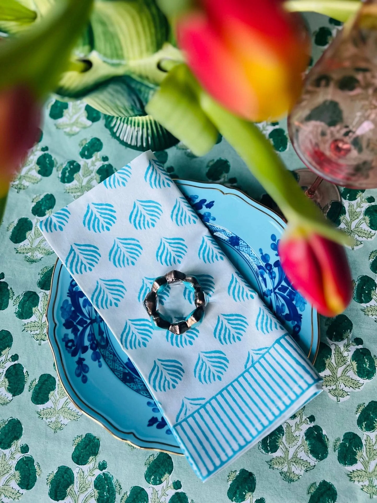 Set of four turquoise Coral Flame napkins by Christina Dickson Home, featuring vibrant coral flame patterns on soft fabric.