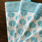 Set of four turquoise Coral Flame napkins by Christina Dickson Home featuring vibrant coral flame pattern.