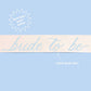 Bride To Be Sash by xo, Fetti with white fabric and gold lettering, designed to be worn around the waist for bridal celebrations.