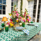 Emerald green Poms tablecloth by Christina Dickson Home, 120x70 inches rectangular fabric laid out on a dining table.