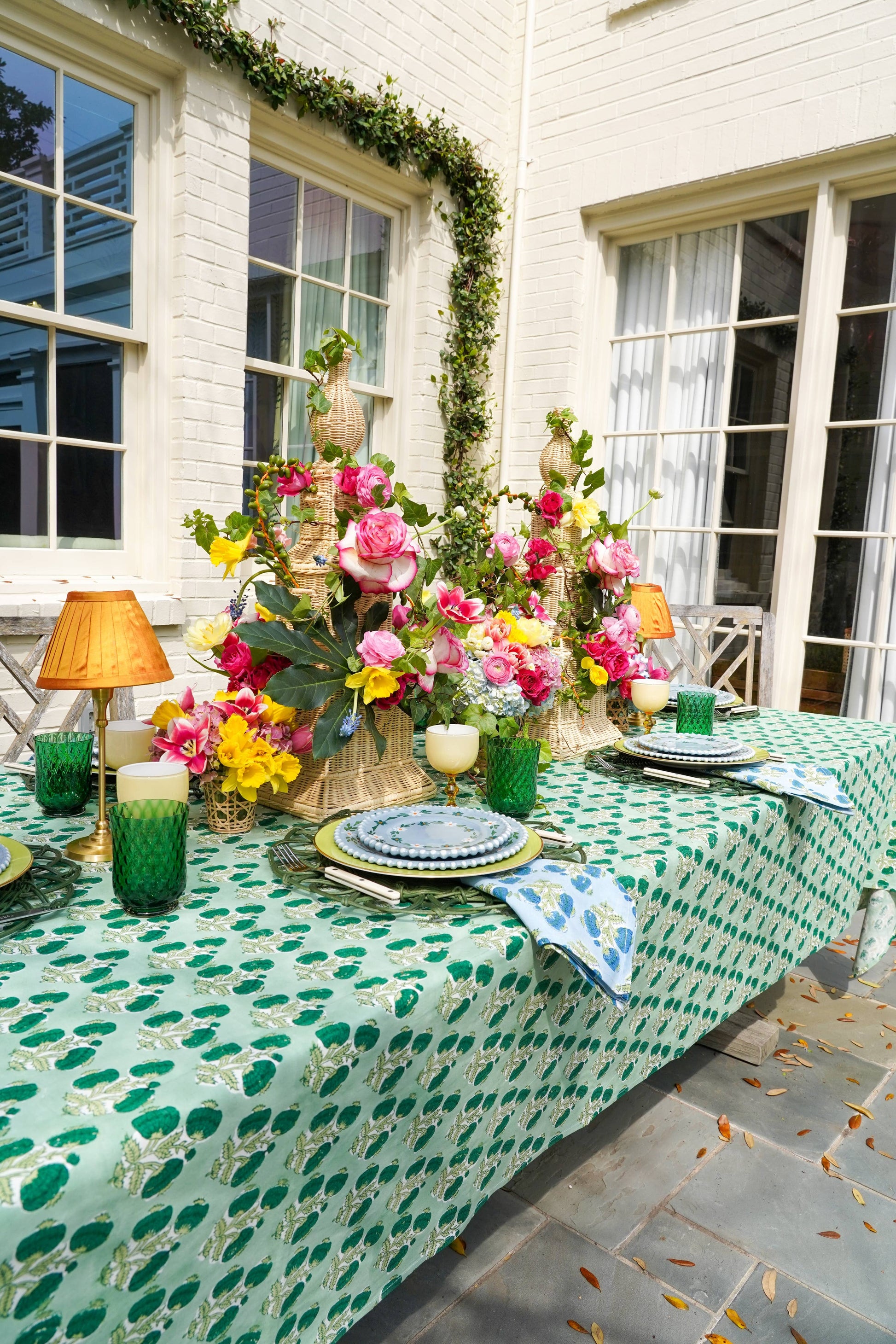 Emerald green Poms tablecloth by Christina Dickson Home, 120x70 inches rectangular fabric laid out on a dining table.