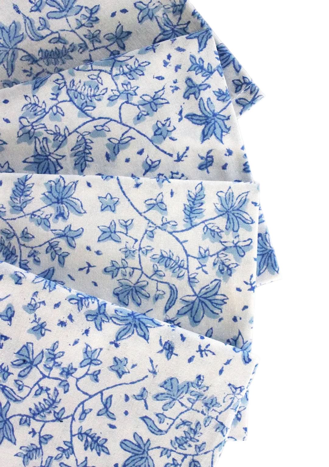 Set of four Christina Dickson Home Whimsy Floral Sorrento Blue napkins with vibrant floral pattern on soft fabric.