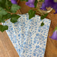 Set of four Christina Dickson Home Whimsy Floral Napkins in Sorrento Blue with vibrant floral patterns on soft fabric.