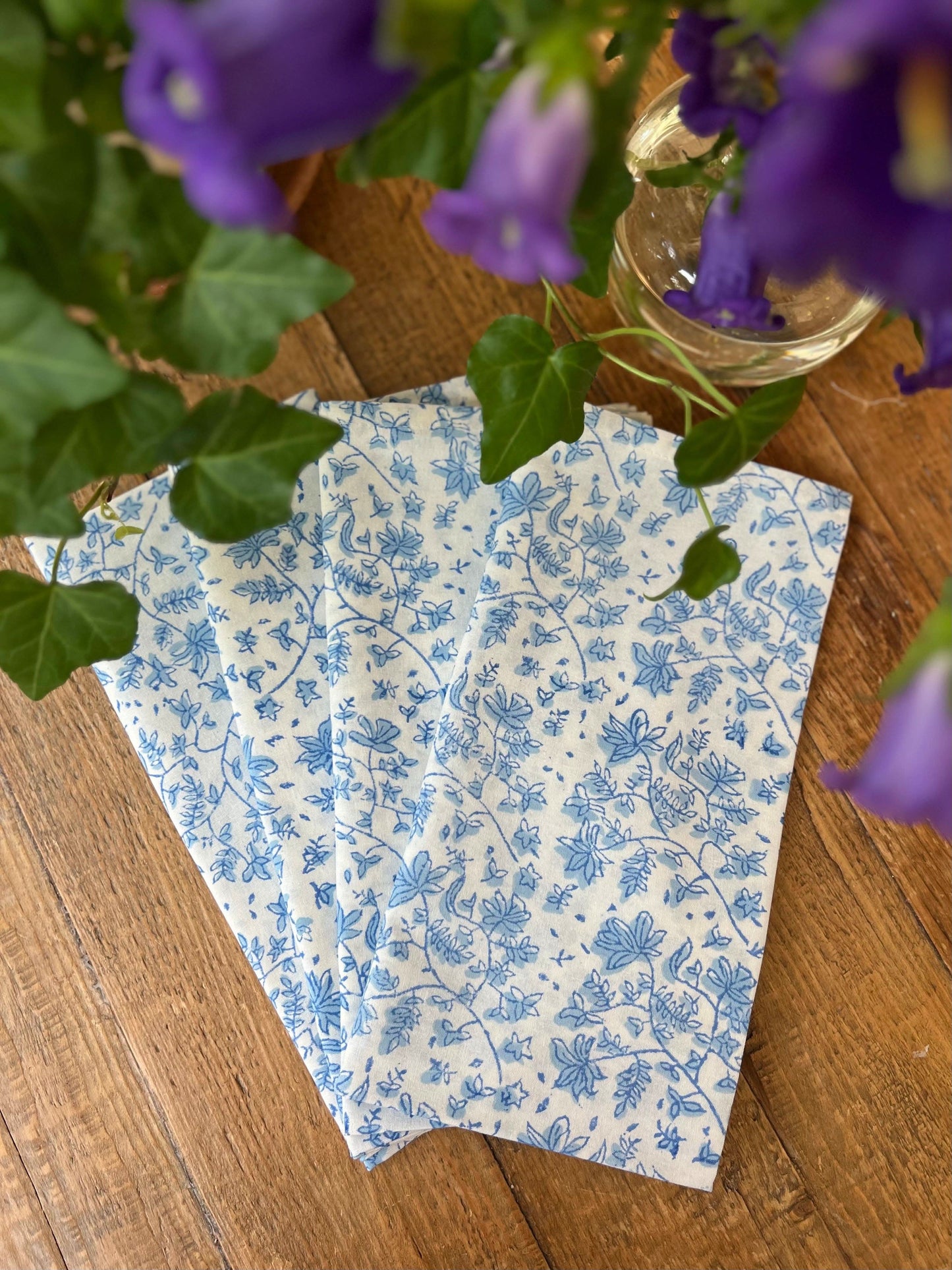 Set of four Christina Dickson Home Whimsy Floral Napkins in Sorrento Blue with vibrant floral patterns on soft fabric.