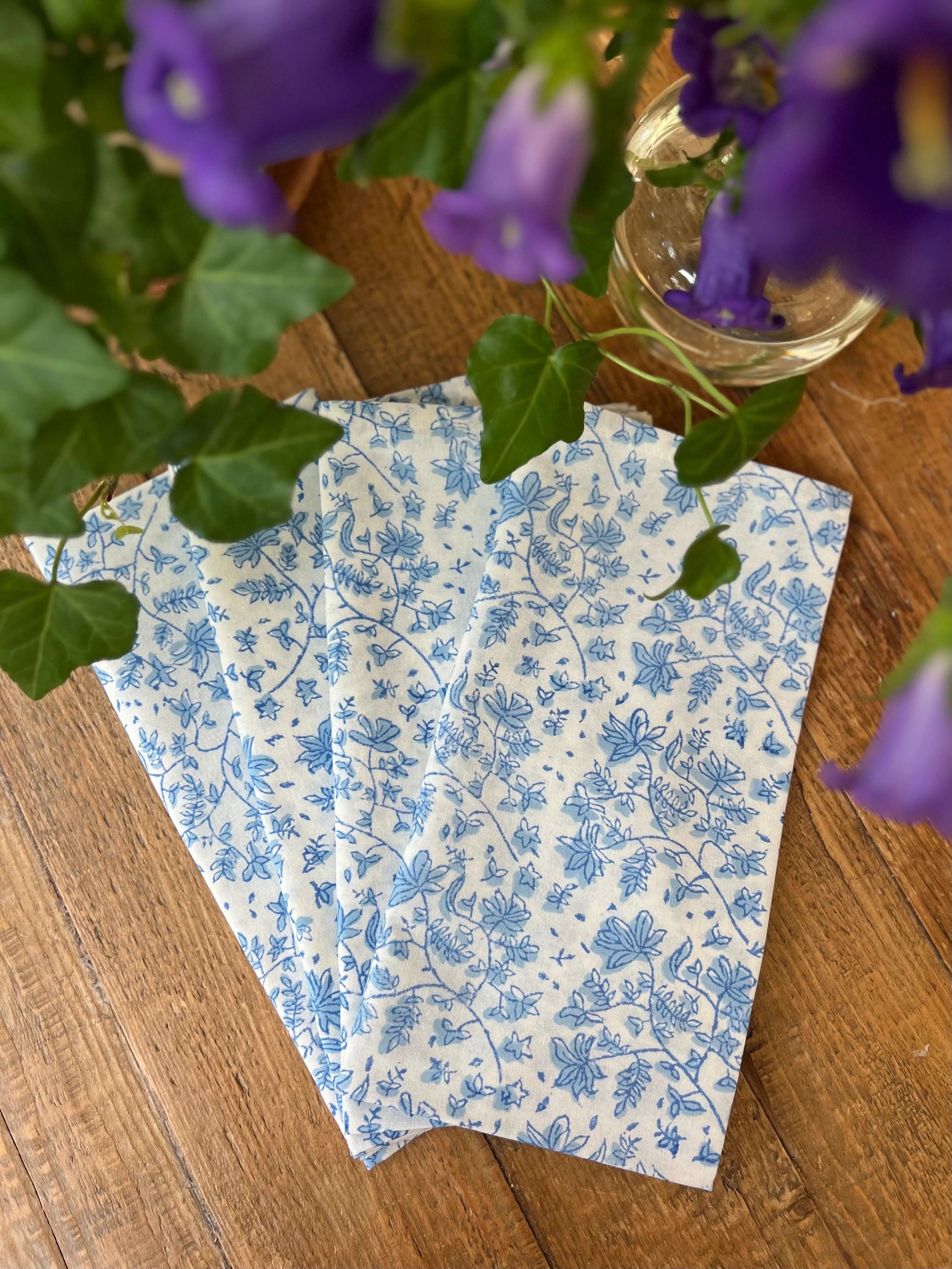 Set of four Christina Dickson Home Whimsy Floral Napkins in Sorrento Blue with vibrant floral patterns on soft fabric.