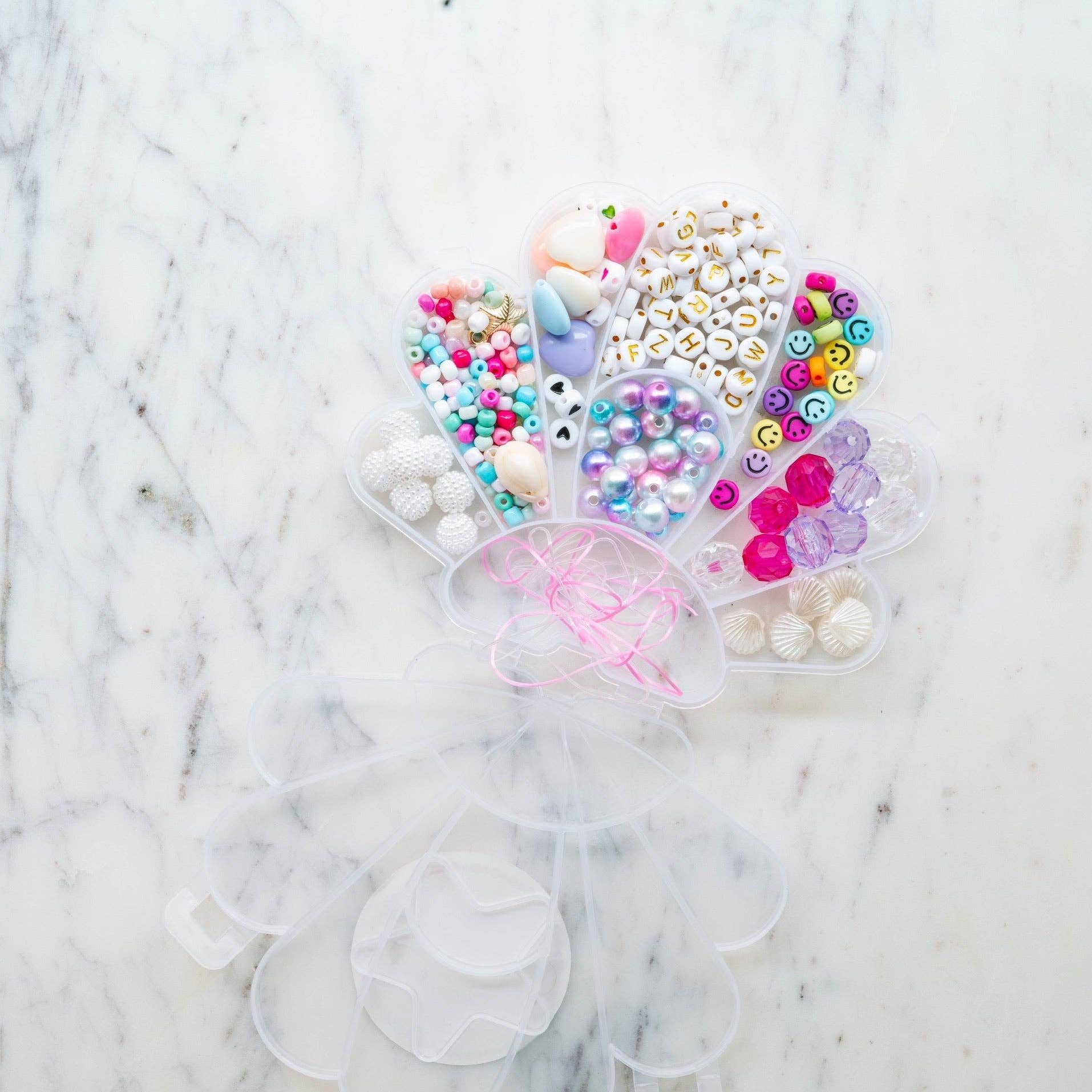 Little Stacks The Shell Kit featuring colorful plastic shells and a storage container for creative play and organization.
